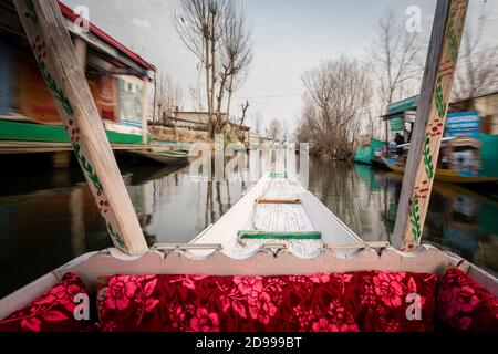 Una vista dall'interno di uno shikara con vista offuscata dell'acqua circostante e l'edificio intorno al lago dal. Foto Stock