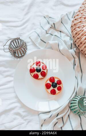 Deliziosi tartine di lamponi con crema ripieno su piatto bianco nel letto. Crostata di frutta fresca su sfondo bianco Foto Stock