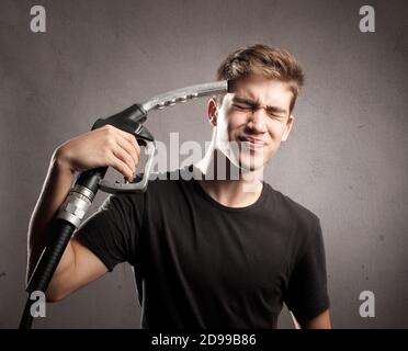 giovane uomo che si spara con un ugello della pompa del carburante Foto Stock