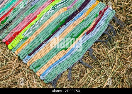 Colorato tappeto lavorato a mano giace su fieno, vista dall'alto Foto Stock