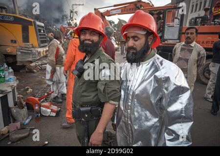 Rawalpindi, Pakistan, dicembre 2008. Vigili del fuoco di fronte a un edificio in fiamme. Foto Stock