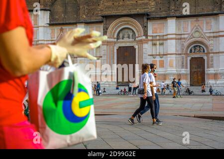 Bologna, Italia - 9 maggio 2020: Guanti e borsa per la quarantena Covid-19 a Bologna. Persone che indossano maschera chirurgica in Piazza maggiore con Foto Stock