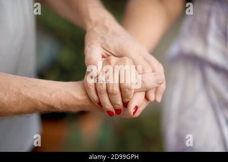 Ripresa ritagliata di una coppia senior che tiene le mani in un parcheggio Foto Stock