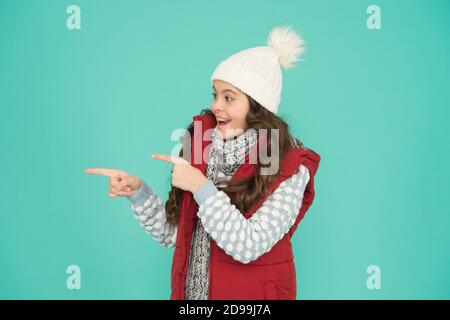 ragazza allegra a strati di vestiti che puntano il dito. spazio copia. abiti caldi durante la stagione invernale. previsioni del tempo freddo. shopping di moda per bambini. tempo di natale. pronto per una vacanza di nuovo anno. senza ipotermia. Foto Stock