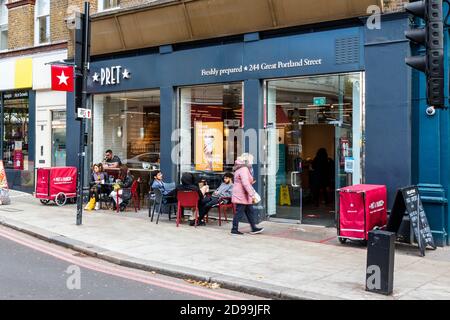 I clienti si siedono sul marciapiede all'esterno di Pret a Manger su Great Portland Street a Fitzrovia, Londra, Regno Unito Foto Stock