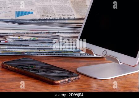 Telefono cellulare, tablet con supporto e quotidiano sulla scrivania. Ricevi le notizie! Foto Stock