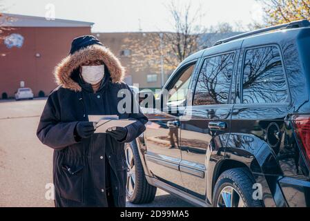 Al di fuori di una stazione di polling alla Dunbar High School a Dayton, Ohio, un volontario per Desiree Tims (D, Ohio) per il Congresso che consegna la letteratura a passare le automobili il giorno delle elezioni. Essendo le elezioni presidenziali nazionali, gli altri candidati sperano di ottenere i voti dell’ultimo minuto facendo delle campagne elettorali nelle sedi elettorali prima della chiusura dei sondaggi. Desiree Tims (D, Ohio) per le campagne del Congresso e parla con i costituenti al di fuori dei seggi elettorali mentre spera di disinsediare Mike Turner (R, Ohio). Foto Stock