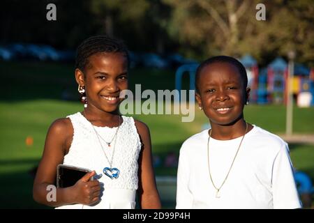 Un ritratto di due bambini afro-americani, di 8-10 anni, tutti vestiti di bianco. Siamo appena tornati da un matrimonio al parco. Brea, California, USA Foto Stock