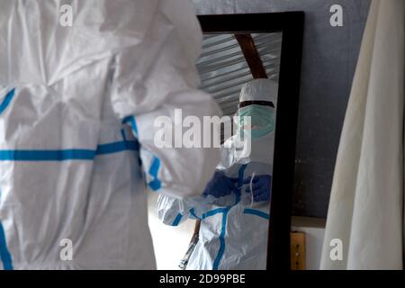 Lunsar, Sierra Leone - 29 aprile 2015: Operaio sanitario africano pronto e indossare indumenti protettivi del PPE durante l'epidemia di ebola. Contesto epidemico e di covidio Foto Stock