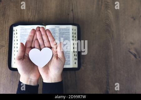 Passa la preghiera femminile per caricare con cuore rotto nelle mani sulla bibbia, il concetto prega per la liberazione, il peccato, nessuna libertà. Foto Stock