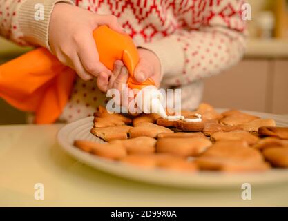 Bambino dipinge un ornamenti di Natale. Processo di cottura del pan di zenzero di Natale Foto Stock