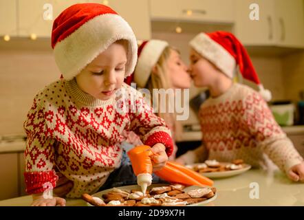 Bella mamma e figli piccoli che decorano gingerbread biscotti natalizi Foto Stock