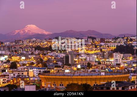 L'arena per la corrida della città di Quito di notte in un quartiere moderno con il vulcano Cayambe, Ecuador. Foto Stock