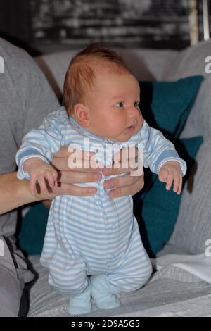 Carino bambino neonato che tiene per le mani del padre Foto Stock