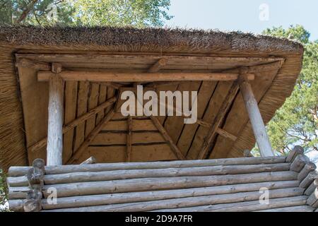 Vintage torre di guardia in legno in legno con tetto di paglia sullo sfondo di cielo blu e alberi a strapiombo. Vista dal basso. Foto Stock