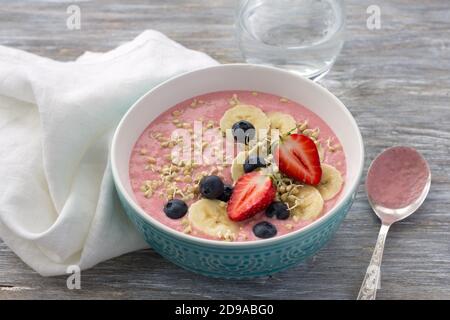 Sana colazione cruda: Porridge di grano saraceno verde germogliato con fragole, mirtilli e banane su un tavolo di legno Foto Stock