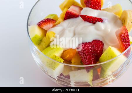 Macedonia di frutta con yogurt naturale in una ciotola di vetro isolata sfondo bianco Foto Stock