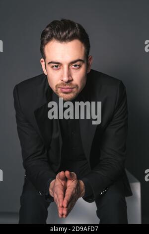 Studio ritratto di un giovane caucasico in una giacca nera, guardando seriamente la macchina fotografica, su uno sfondo di studio semplice Foto Stock