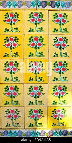 Piastrelle peranakan gialle con un disegno di albero geometrico rosso e verde. Tipico dei mosaici piastrellati che si vedono sulla facciata della tradizionale peranakan Foto Stock