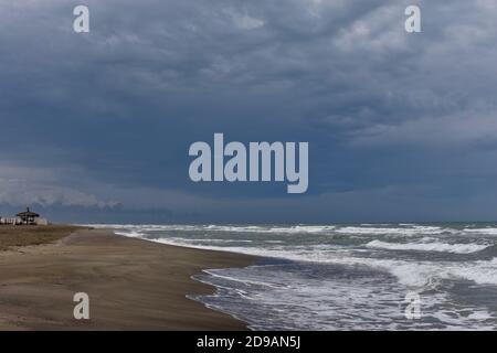 Sulla riva durante una tempesta. Cielo di terra e mare ruvido nella tempesta. Luce scenografica. Su un solitario tratto di spiaggia. Solo un gioco lontano in lontananza. Foto Stock