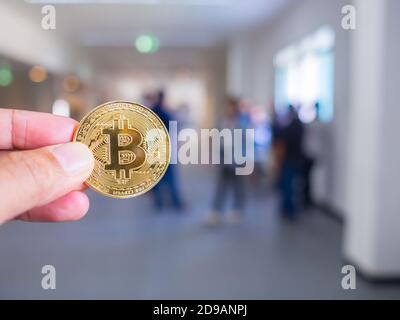 Mano di giovane donna caucasica che tiene una criptovaluta di bitcoin fisica in ufficio. Spazio per il testo. Concetto di tecnologia blockchain. Foto Stock