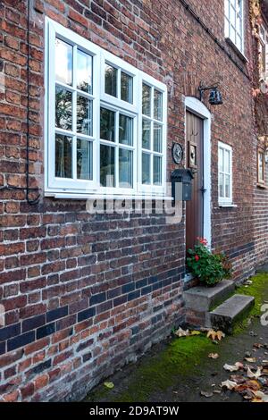 Un cottage a schiera in un villaggio inglese, porta anteriore che si apre sul pavimento Foto Stock