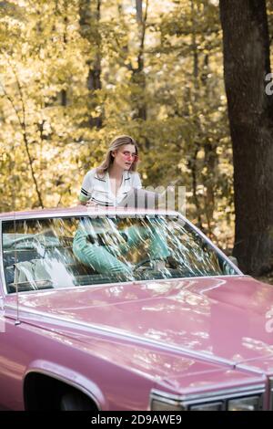 giovane donna seduta in cabriolet e guardando la mappa in foresta Foto Stock