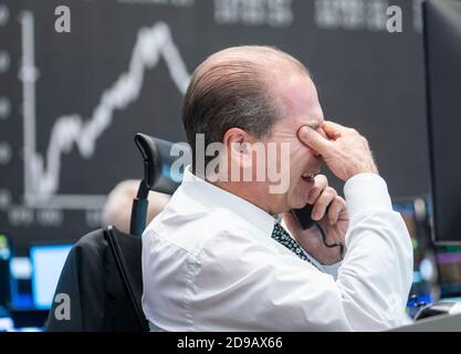 04 novembre 2020, Hessen, Francoforte sul meno: Un commerciante si trova nella sala di negoziazione della Borsa di Francoforte di fronte ai suoi monitor, la curva Dax può essere vista sullo sfondo. Foto: Frank Rumpenhorst/dpa Foto Stock