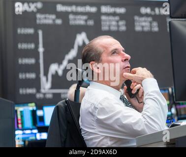 04 novembre 2020, Hessen, Francoforte sul meno: Un commerciante si trova nella sala di negoziazione della Borsa di Francoforte di fronte ai suoi monitor, la curva Dax può essere vista sullo sfondo. Foto: Frank Rumpenhorst/dpa Foto Stock