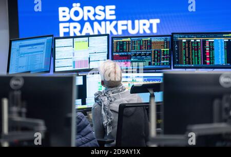 04 novembre 2020, Hessen, Francoforte sul meno: Un commerciante si trova nella sala di negoziazione della Borsa di Francoforte di fronte ai suoi monitor, che mostrano anche relazioni sull'elezione del presidente degli Stati Uniti. Foto: Frank Rumpenhorst/dpa Foto Stock