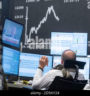 04 novembre 2020, Hessen, Francoforte sul meno: Un commerciante si trova nella sala di negoziazione della Borsa di Francoforte di fronte ai suoi monitor, la curva Dax può essere vista sullo sfondo. Foto: Frank Rumpenhorst/dpa Foto Stock