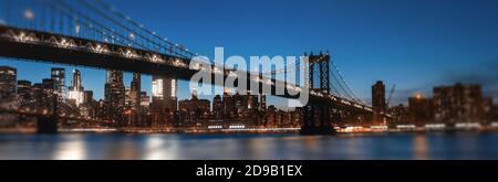 Skyline di Manhattan e Ponte di Manhattan di notte. Immagine sfocata con bordi sfocati e primo piano. Vista romantica con luci e bokeh Foto Stock