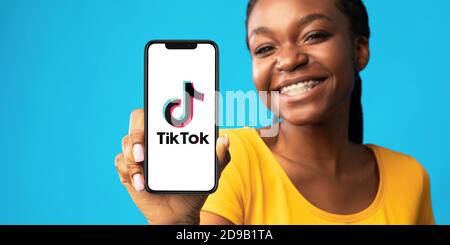 Donna nera con smartphone e app Tik Tok Foto Stock