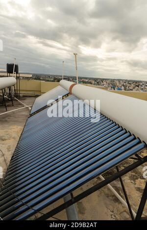 pannelli solari e tubi installati sui tetti della casa e. costruzione di piani per risparmiare energia per il riscaldamento dell'acqua Foto Stock