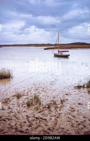 Piccola barca a vela ormeggiata sul fiume Alde a Iken in Suffolk, Inghilterra, Regno Unito Foto Stock