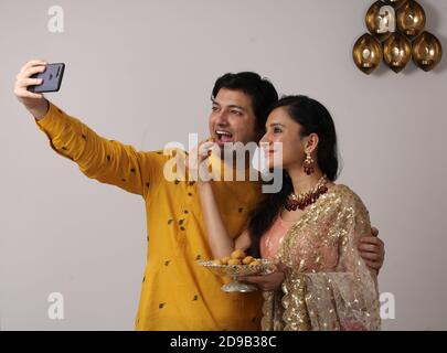 giovane coppia indiana che prende un autoritratto o selfie usando lo smartphone nel festival di diwali. Foto Stock