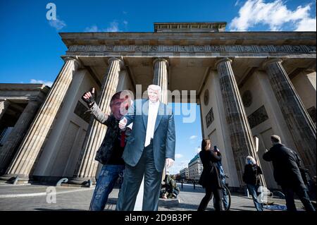 Berlino, Germania. 04Nov 2020. Un sostenitore del presidente americano Trump si presenta di fronte alla porta di Brandeburgo con un cartoncino e una maschera di Trump. Più di 200 milioni di americani sono stati chiamati ad eleggere un nuovo presidente e i membri della Camera dei rappresentanti. Credit: Fabian Sommer/dpa/Alamy Live News Foto Stock