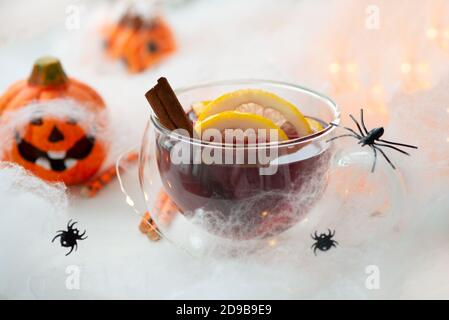 Halloween VIN brulé rosso con spezie e zucche decorate con agrumi su tavolo di legno bianco. Cocktail a sangue rosso Foto Stock