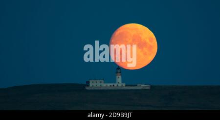 Luna piena che sorge dietro il faro di Copinsay, Orkney Isles Foto Stock