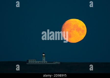 Luna piena che sorge dietro il faro di Copinsay, Orkney Isles Foto Stock