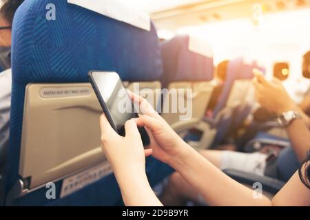Mano della donna che usa lo smartphone sulla messa a fuoco selettiva dell'aeroplano Foto Stock