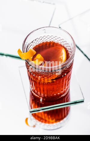 vista ad alto angolo della buccia d'arancia in vetro con alcol cocktail su superficie bianca Foto Stock