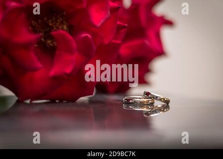 Anelli di nozze e un bouquet di rose rosse Foto Stock