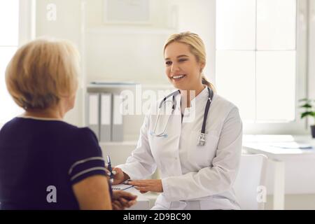 Donna medico seduta e prendere appunti durante la consultazione con maturo paziente donna Foto Stock