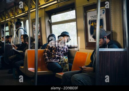 NEW YORK, USA - 28 aprile 2016: Pendolari nel carro della metropolitana di New York. Giovane che ascolta la musica con le cuffie. La metropolitana di NYC e' una delle piu' antiche ed eserte Foto Stock