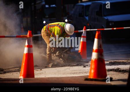 Il lavoratore ha tagliato il calcestruzzo sulla strada durante i lavori stradali all'esterno Nella città degli Stati Uniti Foto Stock