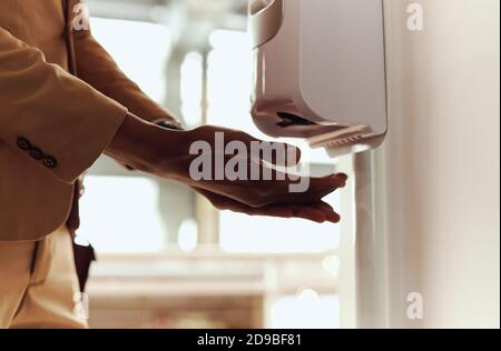 Primo piano di un uomo d'affari che utilizza l'igienizzatore per le mani in un ufficio moderno Durante la Pandemia di salute Foto Stock