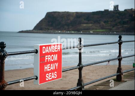 Cartello 'Danger from Heavy Seas' a Scarborough North Bay, Yorkshire, Inghilterra Foto Stock