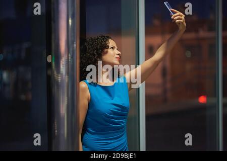 Ritratto notturno nella città di una giovane donna con smartphone. Foto Stock