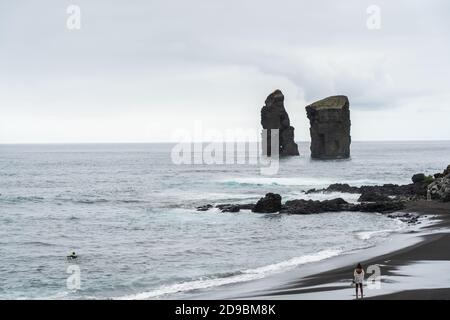 Spiaggia di Mosteiros, spiaggia di sabbia vulcanica a Sao Miguel, Azzorre con le rocce dell'isola Foto Stock